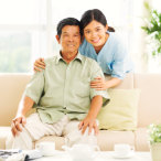 caregiver and senior man sitting on the sofa smiling