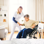 caregiver assisting senior woman to stand up in the wheelchair