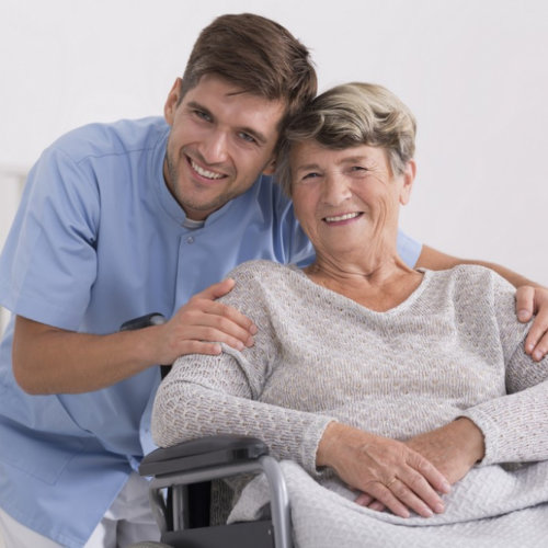 caregiver hugging senior woman sitting in the wheelchair smiling